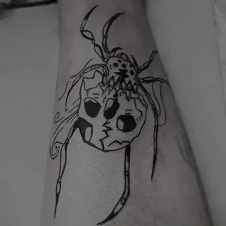 Aranha com caveira no corpo, tatuagem blackwork no antebraço