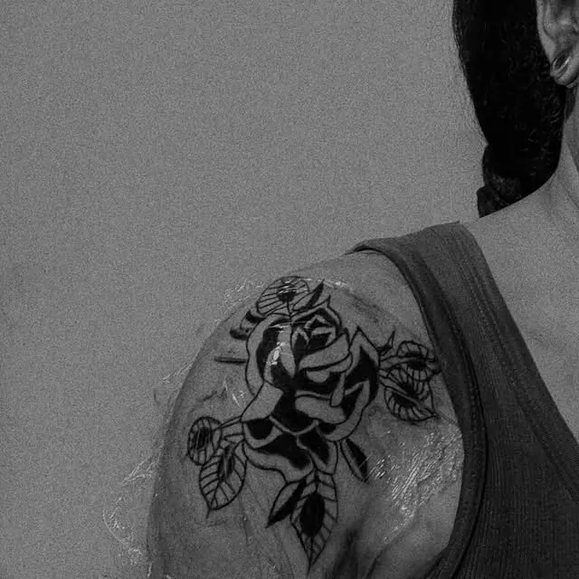 Rosa com folhas em blackwork no ombro