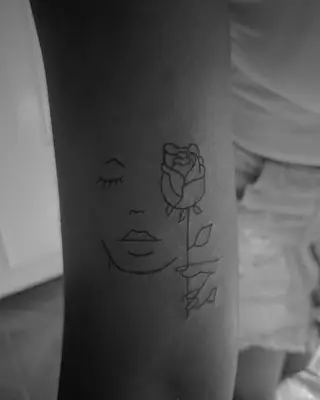 Rosto de olhos fechados ao lado de uma rosa, tatuagem em traço fino